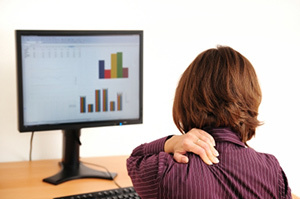 Zervikale Osteochondrose in einer Frau, die vor einem Computer sitzt